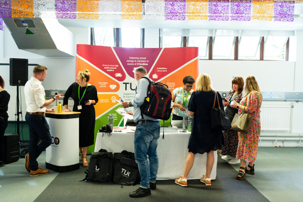Photograph of a busy exhibition stand with bright coloured banners.